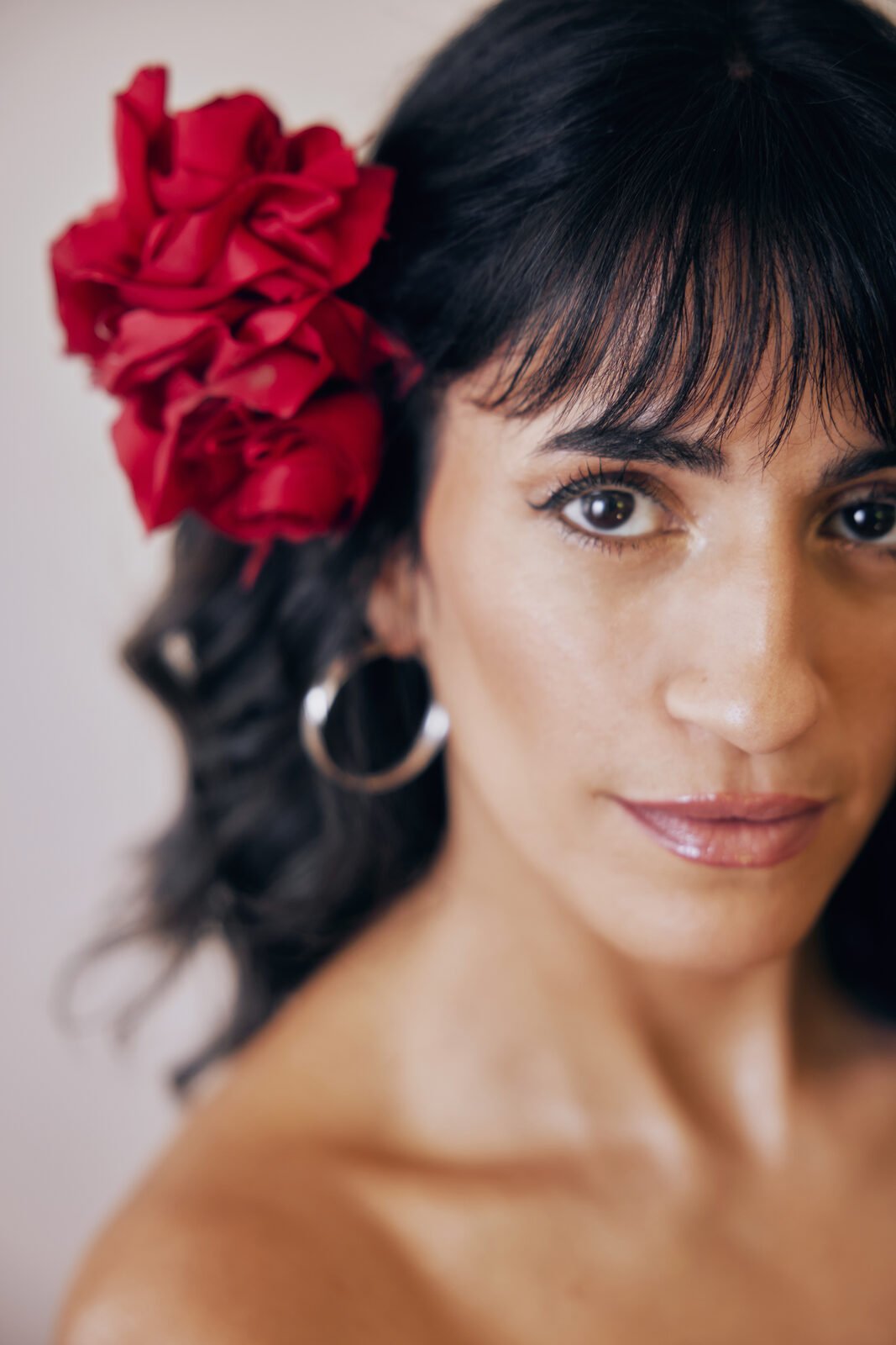 Lu Ferreira mirando directo a cámara con rosa roja en el pelo