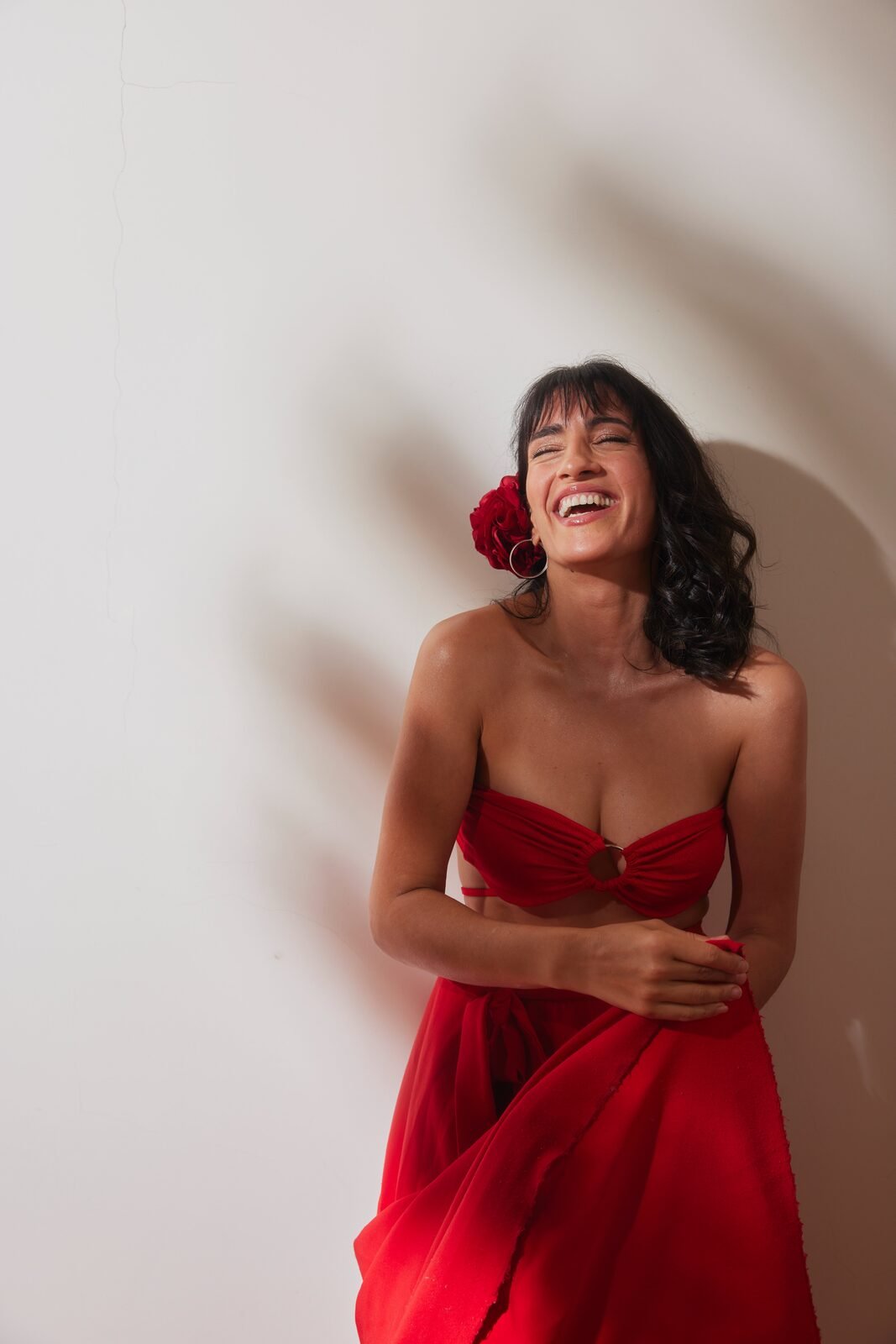 Lu Ferreira riéndose con vestido rojo y rosa en el pelo
